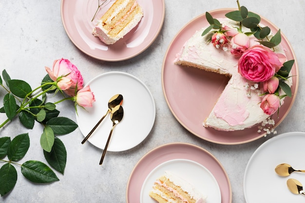 Birthday party concept with rose white cake decorated with pink roses, top down view image