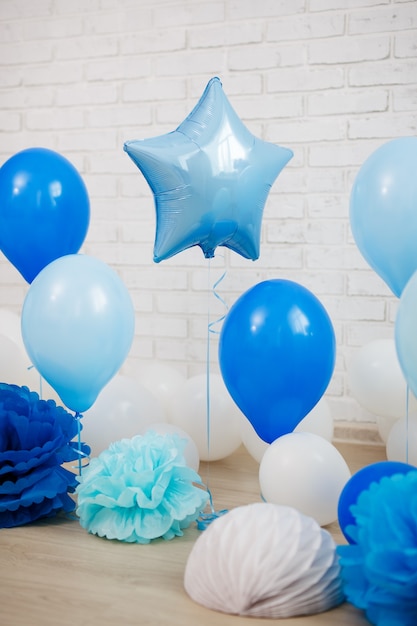 생일 파티 장식 - 흰색 벽돌 벽 배경 위에 파란색 공기 풍선과 종이 공을 닫습니다
