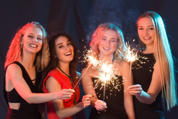 Festa di compleanno, capodanno e concetto di vacanze - gruppo di amiche che celebrano le stelle filanti in mano.