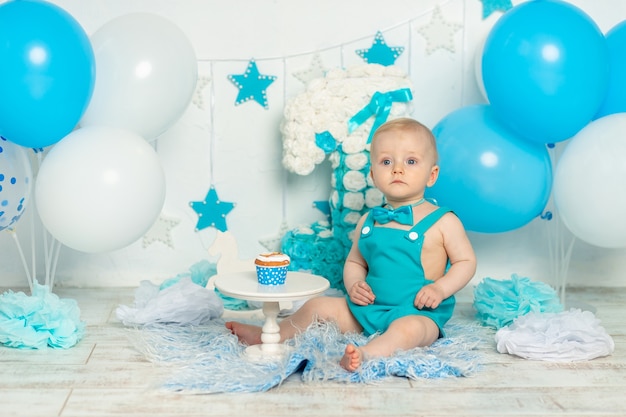 Birthday party one year old boy in blue with balloons and cake, holiday and decor concept, baby with cake