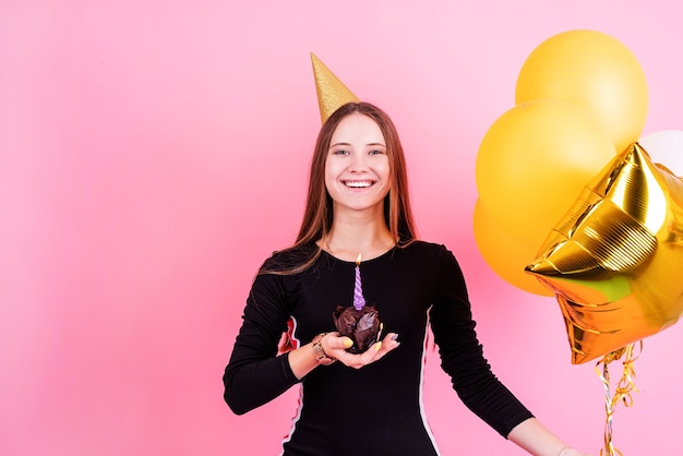 Фото Вечеринка в честь дня рождения. именинница-подросток с кексом и золотыми шарами