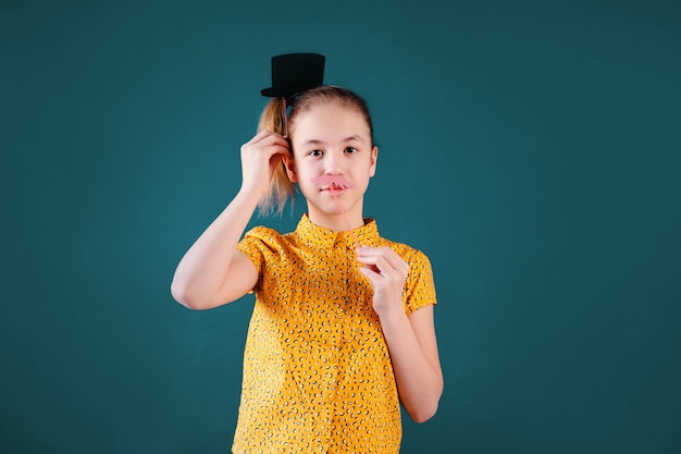 Festa di compleanno e ragazza in cappelli e oggetti di scena sulla parete blu