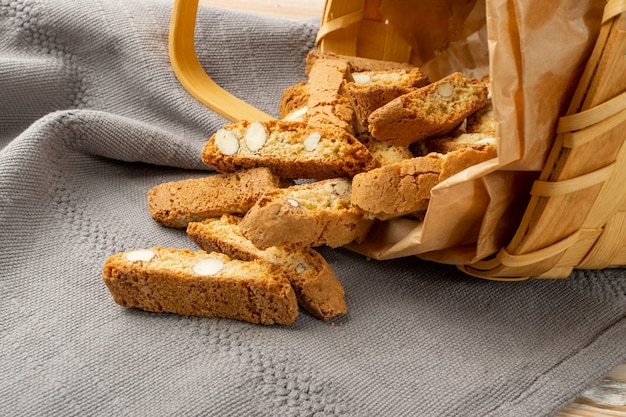 Biscotti di prato op rustieke tafelkleed jute achtergrond. Traditionele Italiaanse cantuccini-notenkoekjes. Zelfgemaakte cantucci zandkoek met amandel in een rieten mand