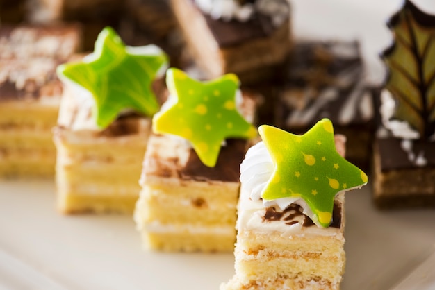 Biscuit cake, decorated with cream and white chocolate on a white plate. Selective focus