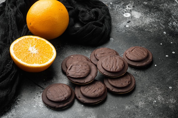 Biscuit filled with orange topped with chocolate on black dark stone table background