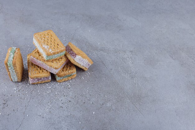 Biscotto panino farcito con marmellata di arance colorate su sfondo di pietra.