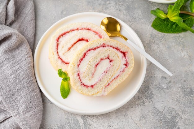 Biscuitbroodje met aardbeienjam en room op een witte plaat op een grijze achtergrond