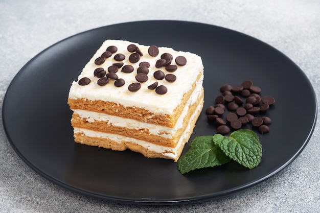 Biscuitgebak met botercrème en chocoladestukjes munt op een zwarte plaat. Dessert voor het vieren van een evenement of verjaardagsfeestje.