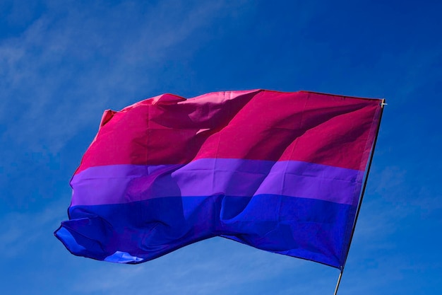 Bisexual flag fluttering in the wind over a blue sky.