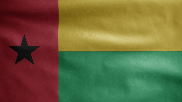 Photo bissau guinean flag waving in the wind. close up of guinea bisau banner blowing, soft and smooth silk. cloth fabric texture ensign background.