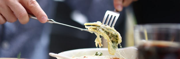 Bistro bezoeker zittend aan tafel met mes en vork met stuk bolognese