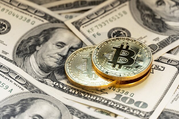 Bitcoin sullo sfondo di 100 fatture del dollaro.