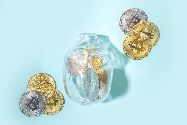 Bitcoin background, cryptocurrency virtual currency market concept. Gold silver bitcoin coins with piggy bank on the background of a laptop with an exchange chart