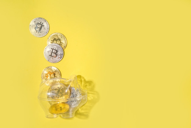 Bitcoin background, cryptocurrency virtual currency market concept. Gold silver bitcoin coins with piggy bank on the background of a laptop with an exchange chart