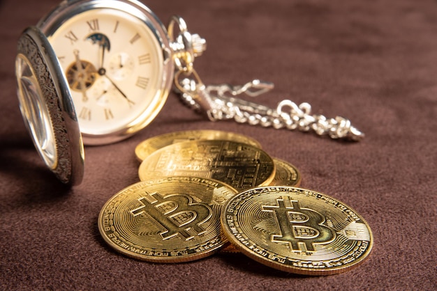 Monete bitcoin bitcoin e un orologio da tasca vintage posizionato su un fuoco selettivo di sfondo in pelle marrone