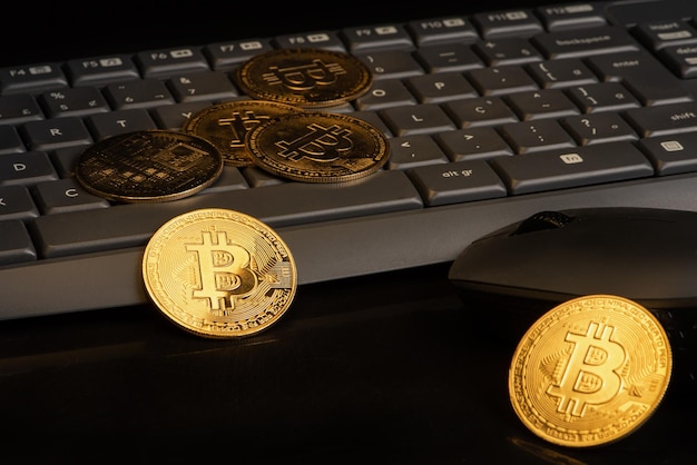 Bitcoin bitcoin coins with a computer keyboard and mouse placed on a dark background selective focus