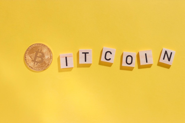 Bitcoin coin inscription in wooden letters on yellow background with hard shadows top view