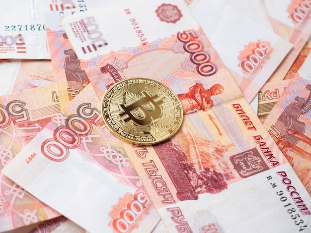 The bitcoin coin lies on the background of Russian rubles. Cryptocurrency mining and Mining Concept