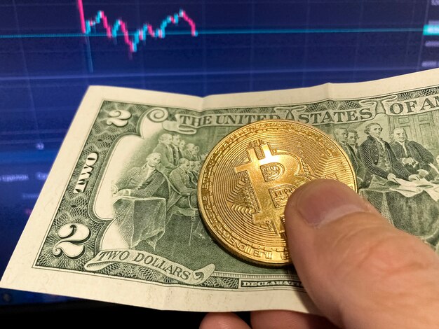 Bitcoin coin on paper bill two Dollars. Selective focus. The electronic schedule of bitcoin, volume trades