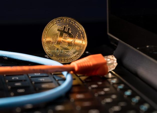 Bitcoin coin standing on keyboard of computer