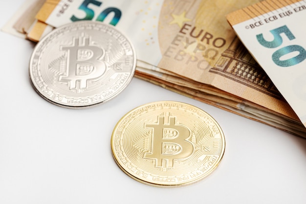 Bitcoin coins and Euro banknotes. Cryptocurrency versus fiat money concept