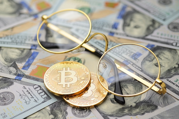 Monete ed occhiali di bitcoin sopra i soldi del dollaro