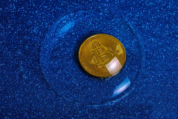 Foto bitcoin cryptocurrency munt in een zeepbel op een blauwe achtergrond.