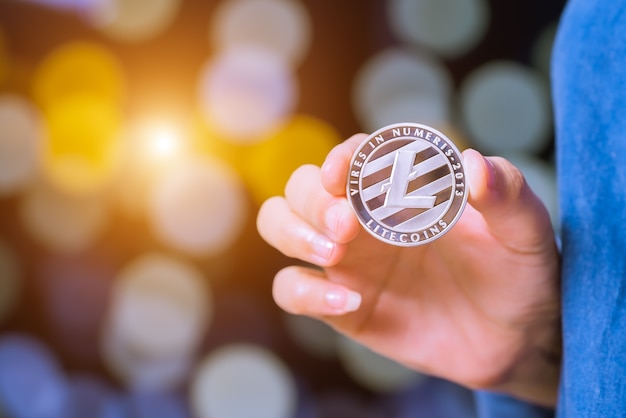 Bitcoin, Ethereum, Litecoin, Ripple. Women hold the cryptocurrency coin on hand