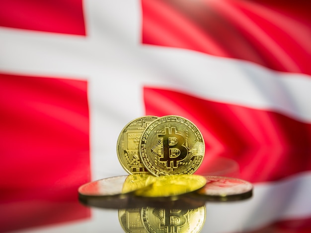 Bitcoin moneta d'oro e bandiera sfocata dello sfondo della danimarca. concetto di criptovaluta virtuale.