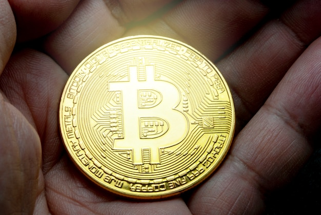 Bitcoin goud in de hand met zwarte wazig patroon achtergrond