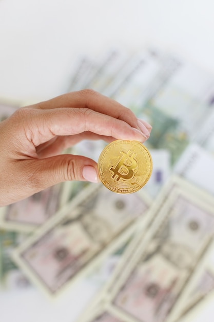 Bitcoin in de hand tegen de achtergrond van geld