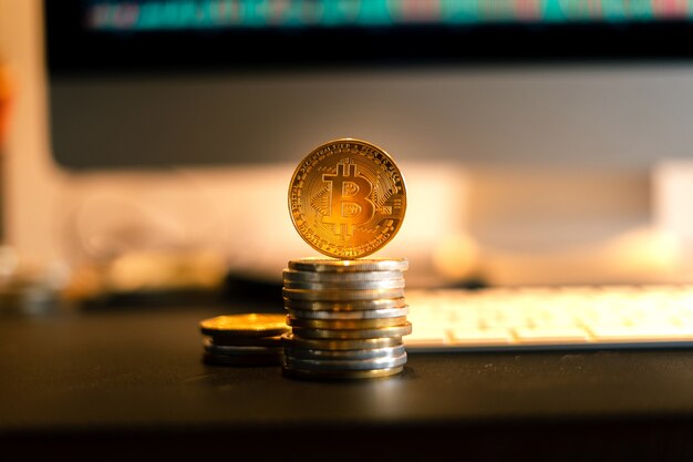 Bitcoin is placed on a desk in front of a computer graph