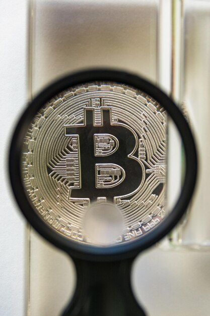 Photo bitcoin metal coin under glass prism and magnifying glass