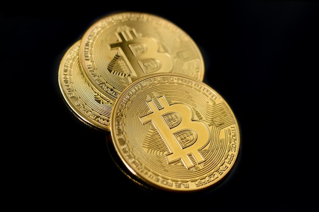 Bitcoin munten op zwarte achtergrond. Drie gouden bitcoin munten close-up. cryptogeld