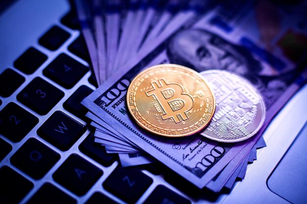 Bitcoin op een laptoptoetsenbord en honderd-dollarbiljetten in neonlicht.