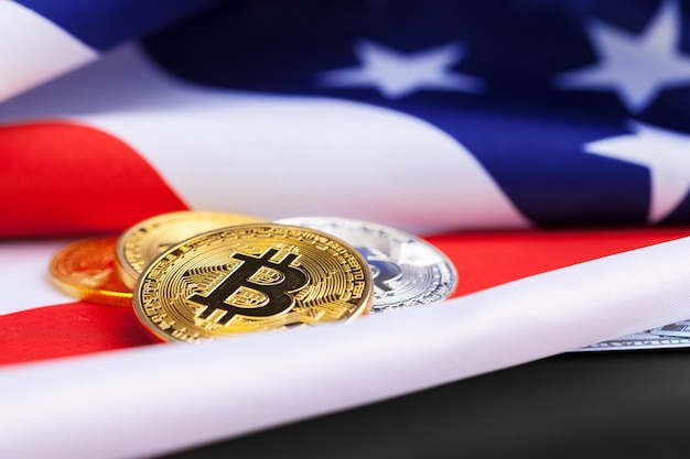 Monete fisiche di bitcoin sul fondo della bandiera americana con i dollari