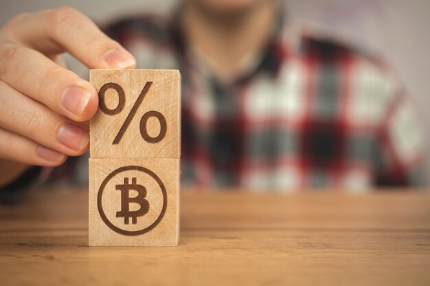 Bitcoin and taxes concept background us taxation Wooden cubes with bitcoin and percent symbols in hands closeup view business photo