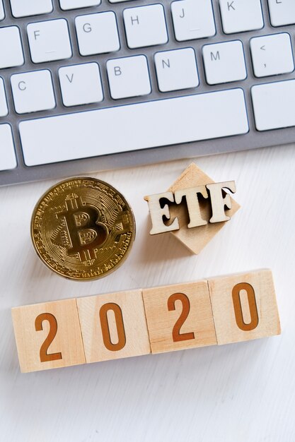 Bitcoin with numbers on cubes on a white keyboard wooden background