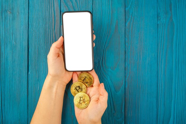 Bitcoin woman with mobile phone and golden coin and bitcoin in hands