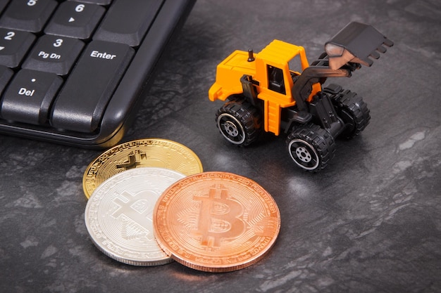 Bitcoins als symbool van elektronisch virtueel geld miniatuur graafmachine en computer toetsenbord mining cryptocurrency concept