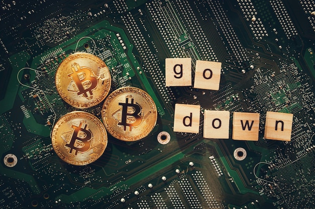 Bitcoins on the background of a computer chip goes down