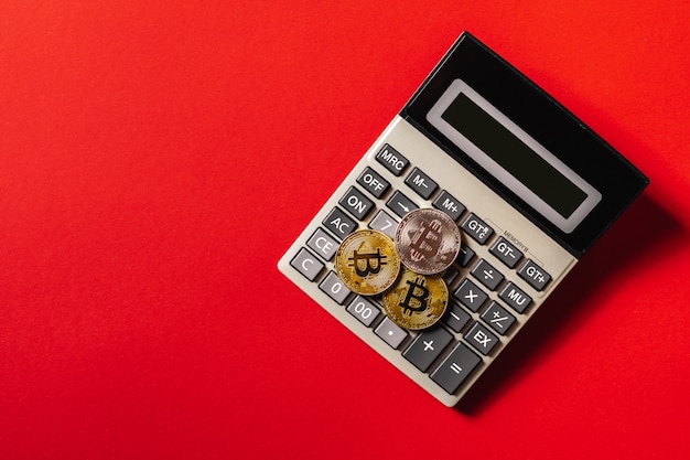 bitcoins and calculator on a red table