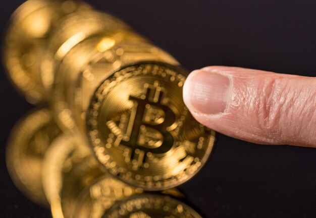 Foto bitcoins die op een rij staan als dominostenen met vinger