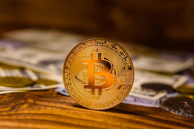 Bitcoins and one hundred dollar bills on wooden table