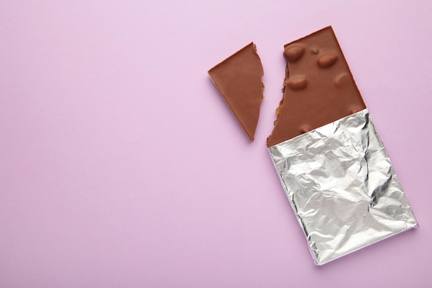 Bitten Chocolate bar in foil on purple background With clipping path