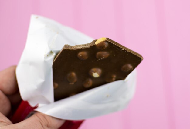 Foto una barretta di cioccolato morso con noci su sfondo rosa