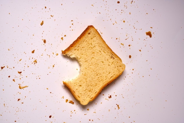 Укушенный ломтик тостового хлеба на белом изолированном фоне.