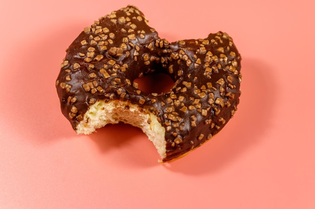 Bitten tasty chocolate donut on a pink background