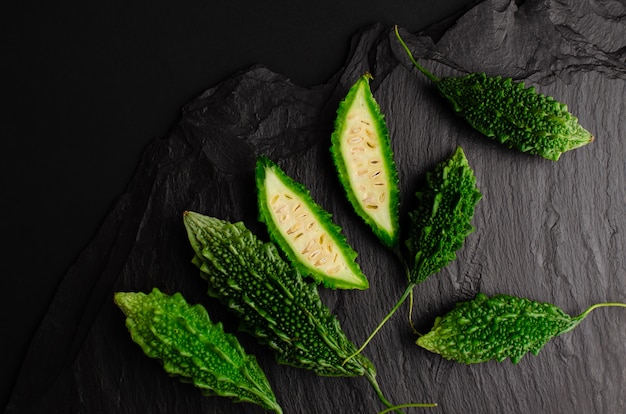 Bitter cucumber on black slate background. Exotic cuisine . Copy space, flat lay