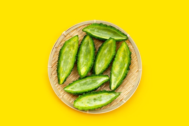 Bitter gourd in bamboo basket on yellow background.